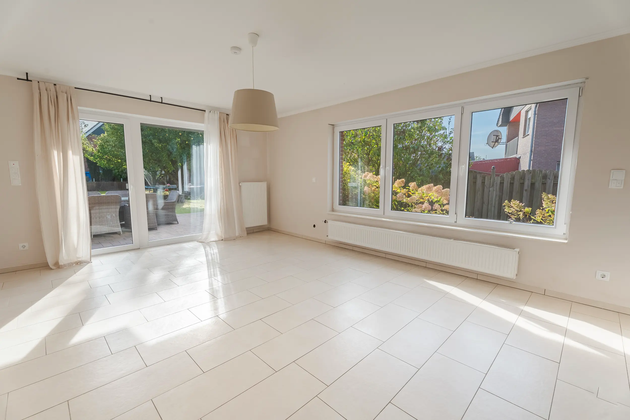 Lichtdurchflutetes Wohnzimmer im Einfamilienhaus in Südlohn-Oeding mit Gartenblick durch Fenster und Terrassentür.+