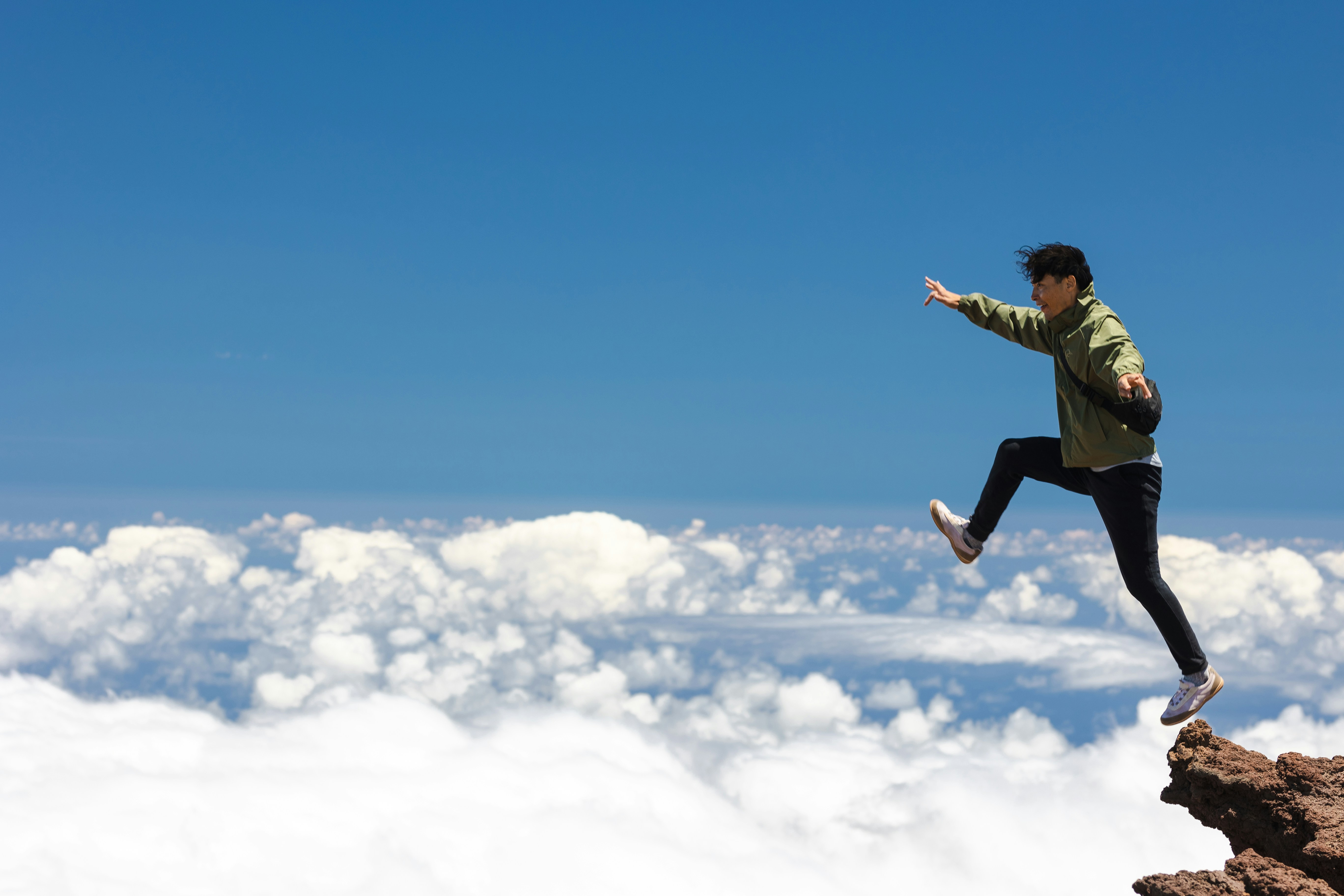Person jumping above clouds