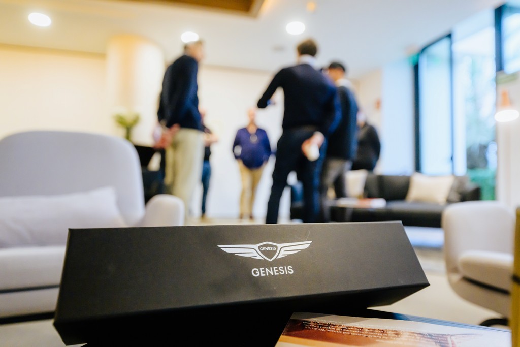 Genesis gift box takes center stage, with business guests in the backdrop – a branding element at a premium client event.