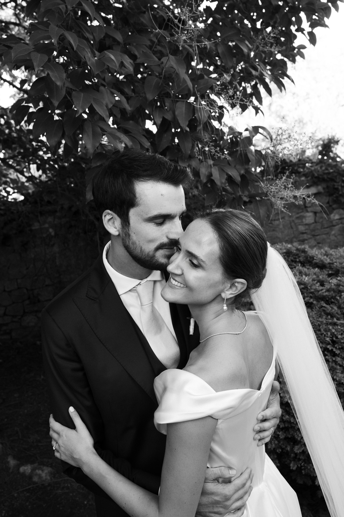 Sposi abbracciati sotto gli alberi al Castello di Scipione, ritratto matrimoniale in bianco e nero con luce naturale