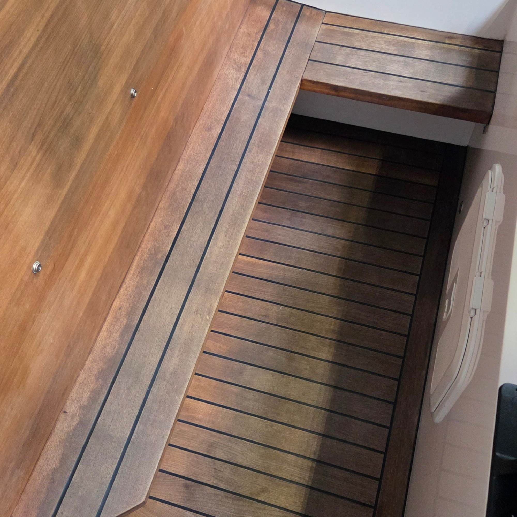 Teak flooring in a boat that is dry and damaged and old.