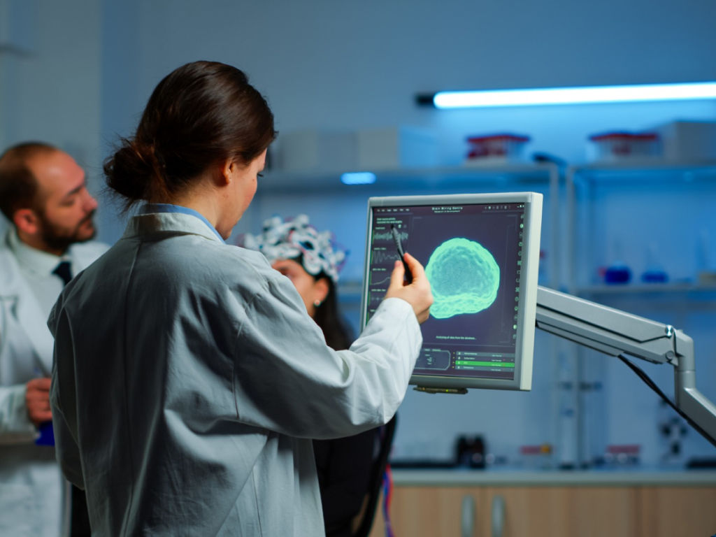 A woman in a lab coat analyzing data on a computer screen.