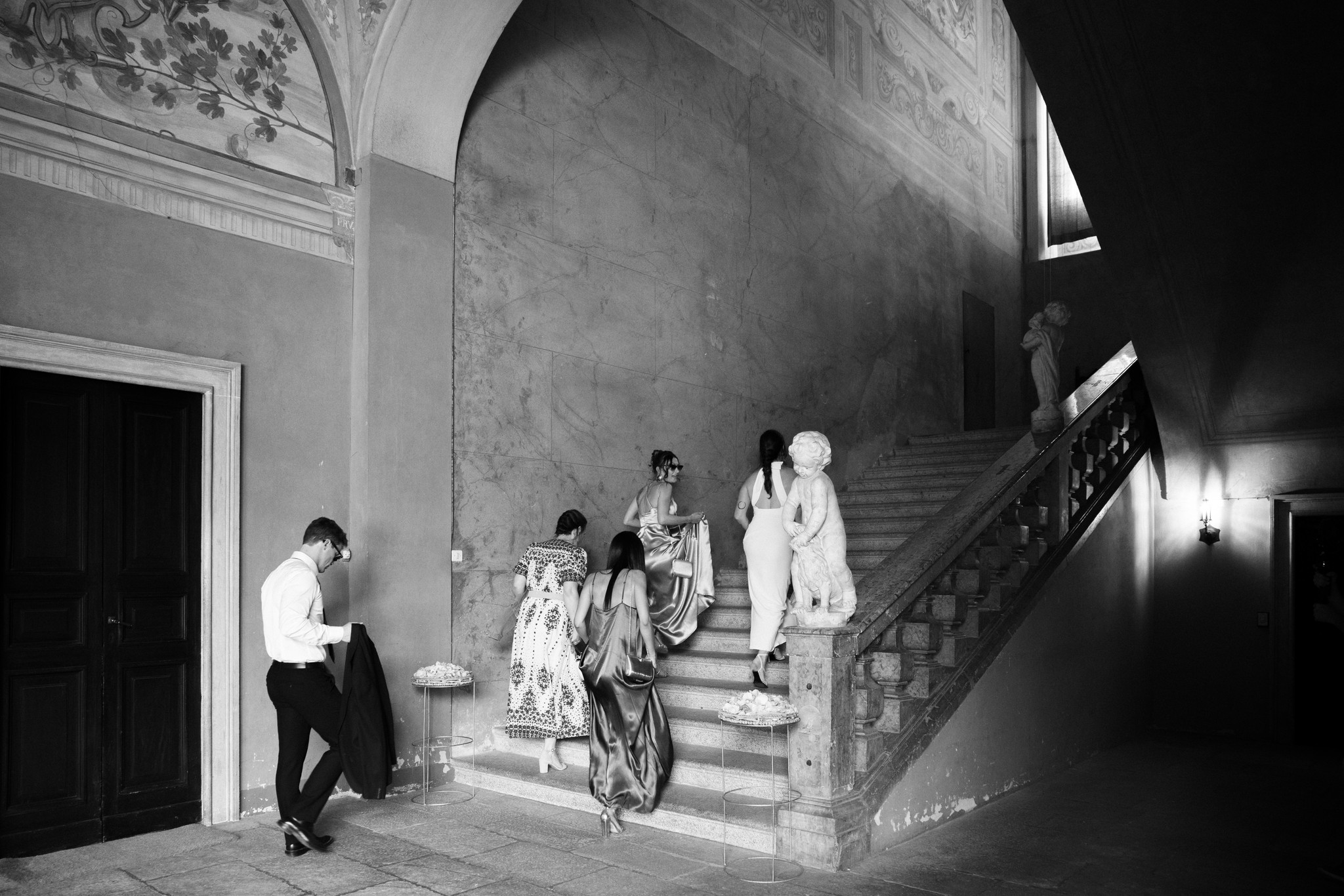 Sposi scendono la scala monumentale della Rocca di Soragna dopo la cerimonia, ospiti seguono nel reportage matrimoniale