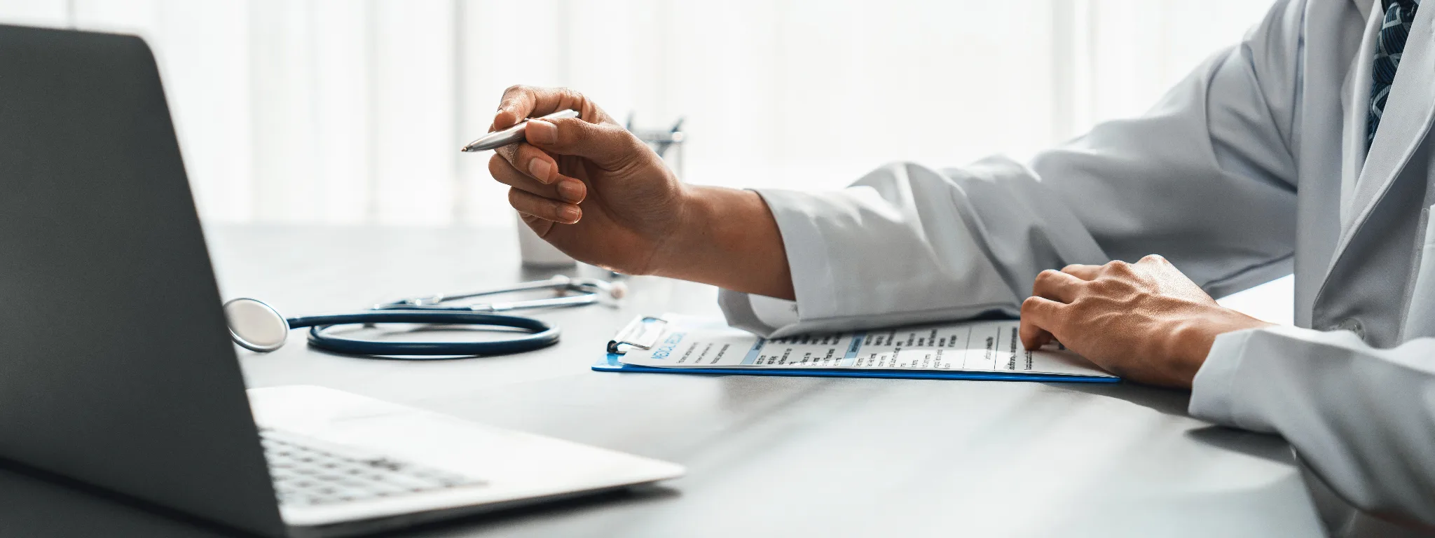 Cropped photo of the hand of a doctor filling out a document.