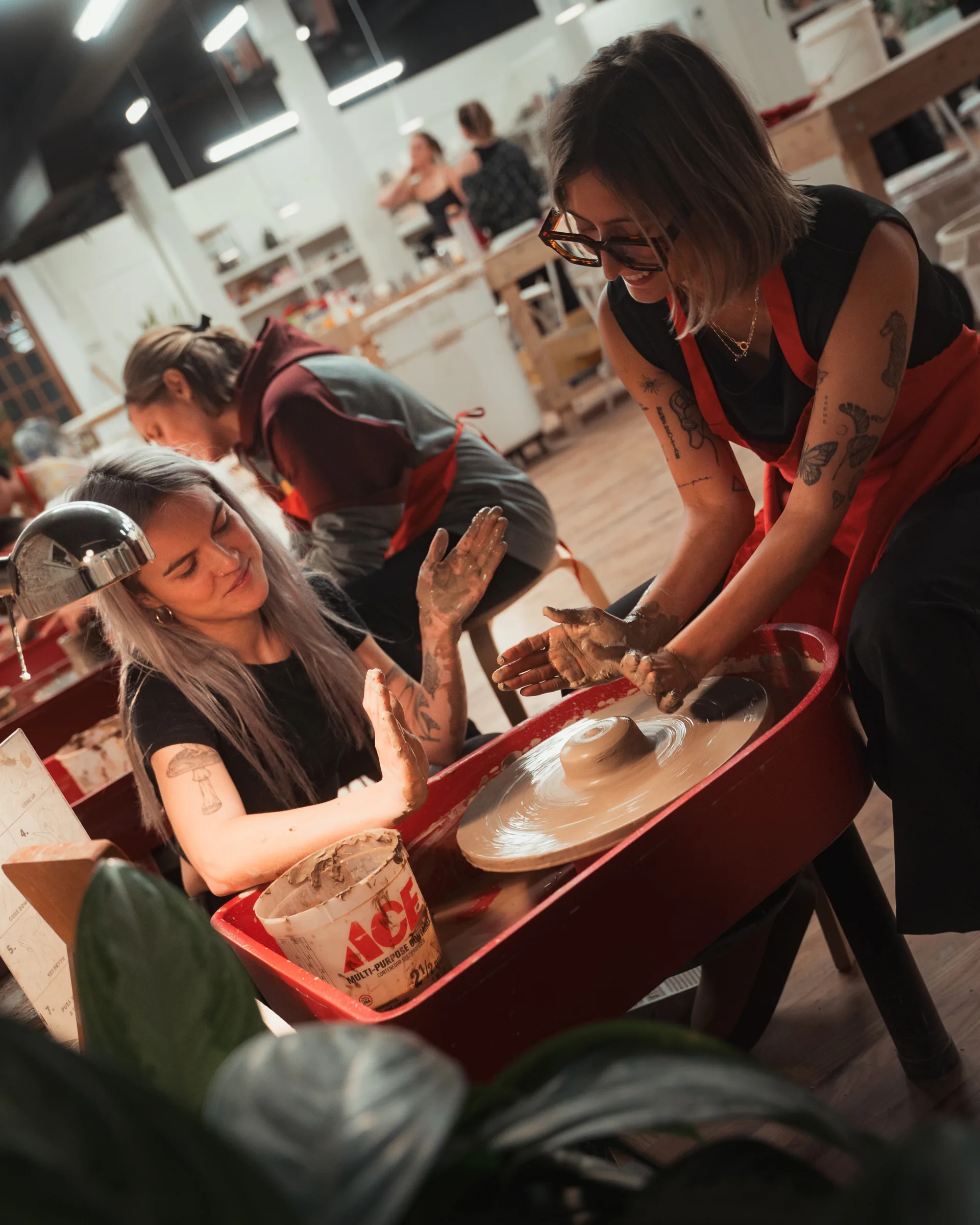 Kinship instructor guiding a student through a private pottery lesson at the wheel in Denver