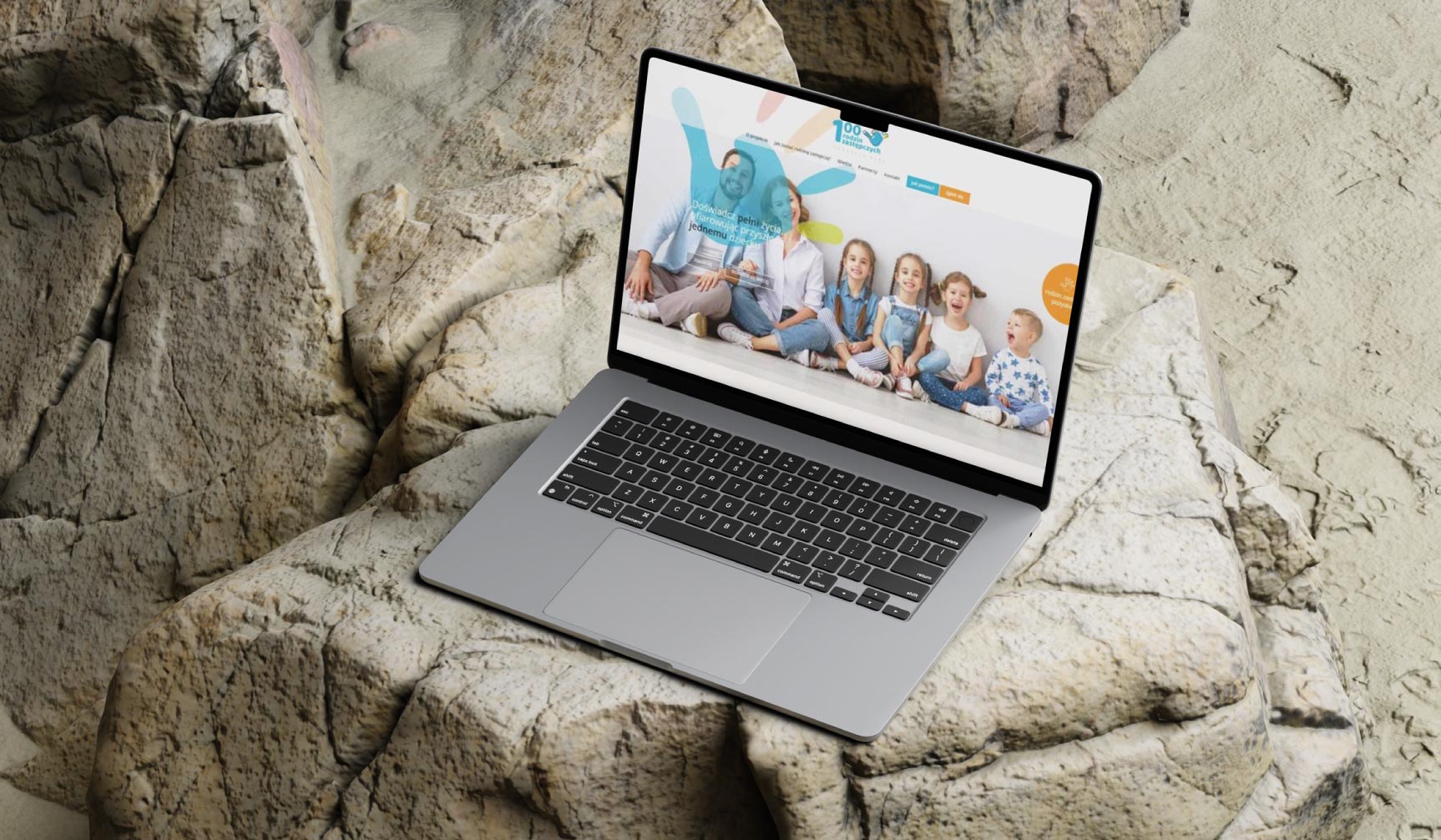 Prezentacja responsywnej strony internetowej (RWD) o tematyce rodzinnej – mockup laptopa w scenerii plenerowej (na skałach).