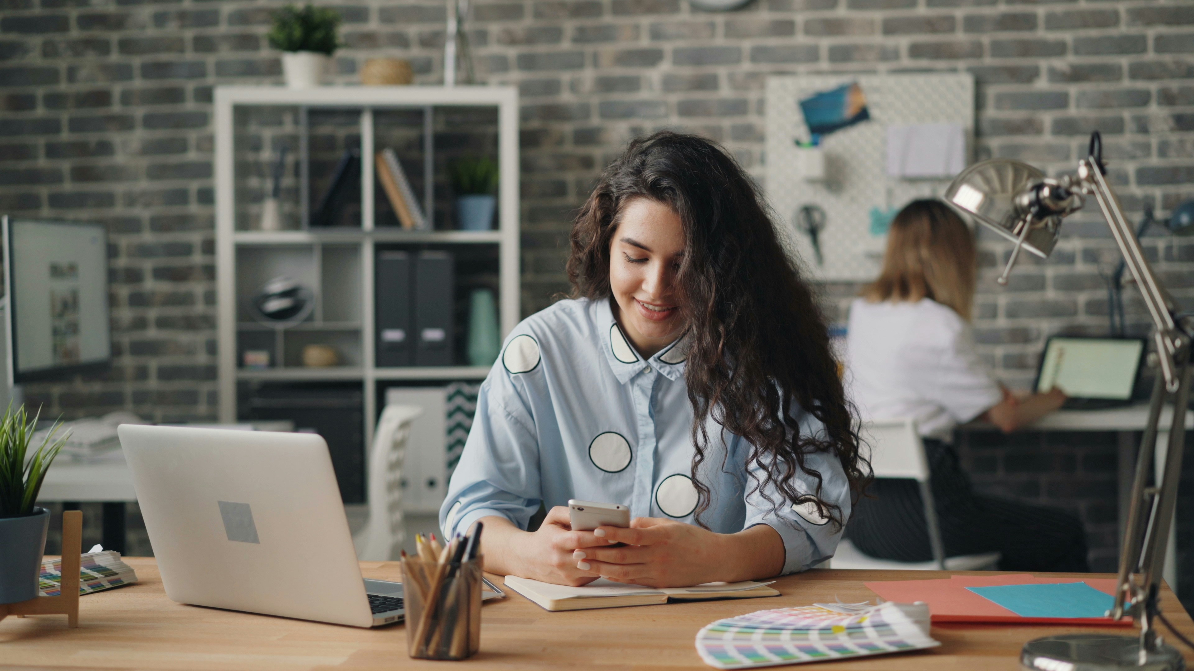 woman at her desk on phone - Jasper AI Alternative