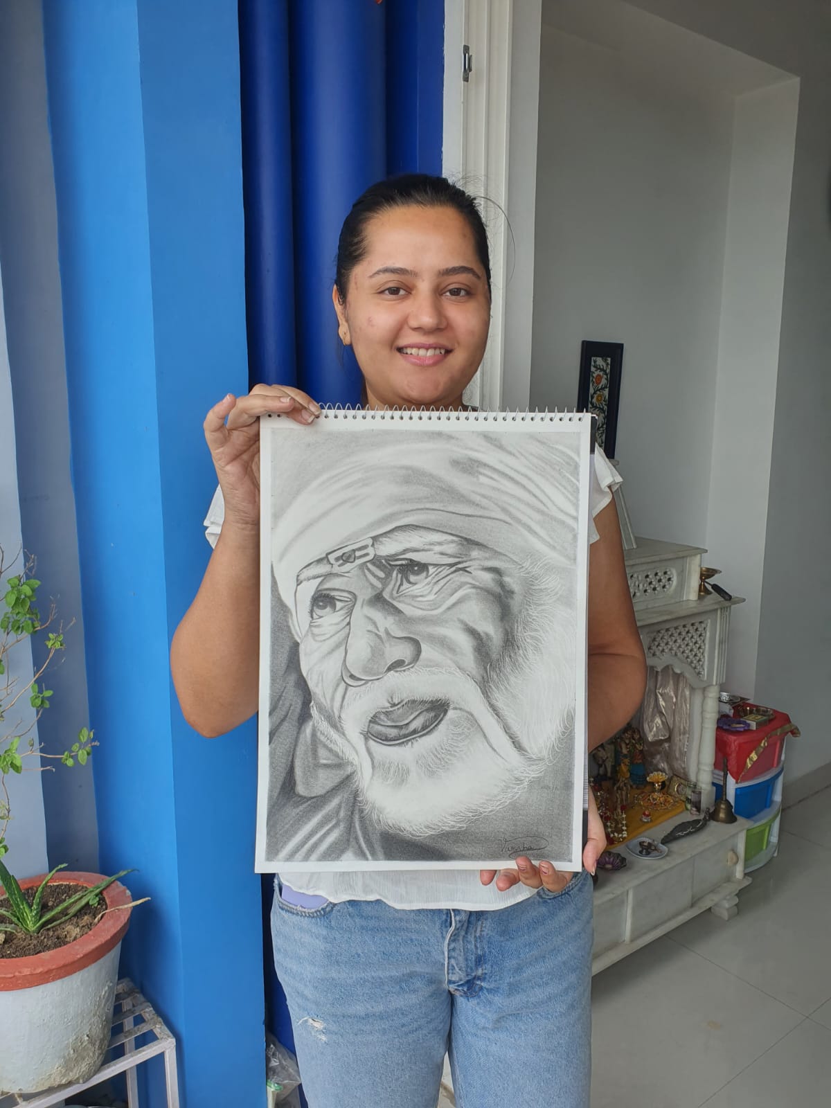 A person holds a sketch of Sai Baba, standing in the Creative Pod studio