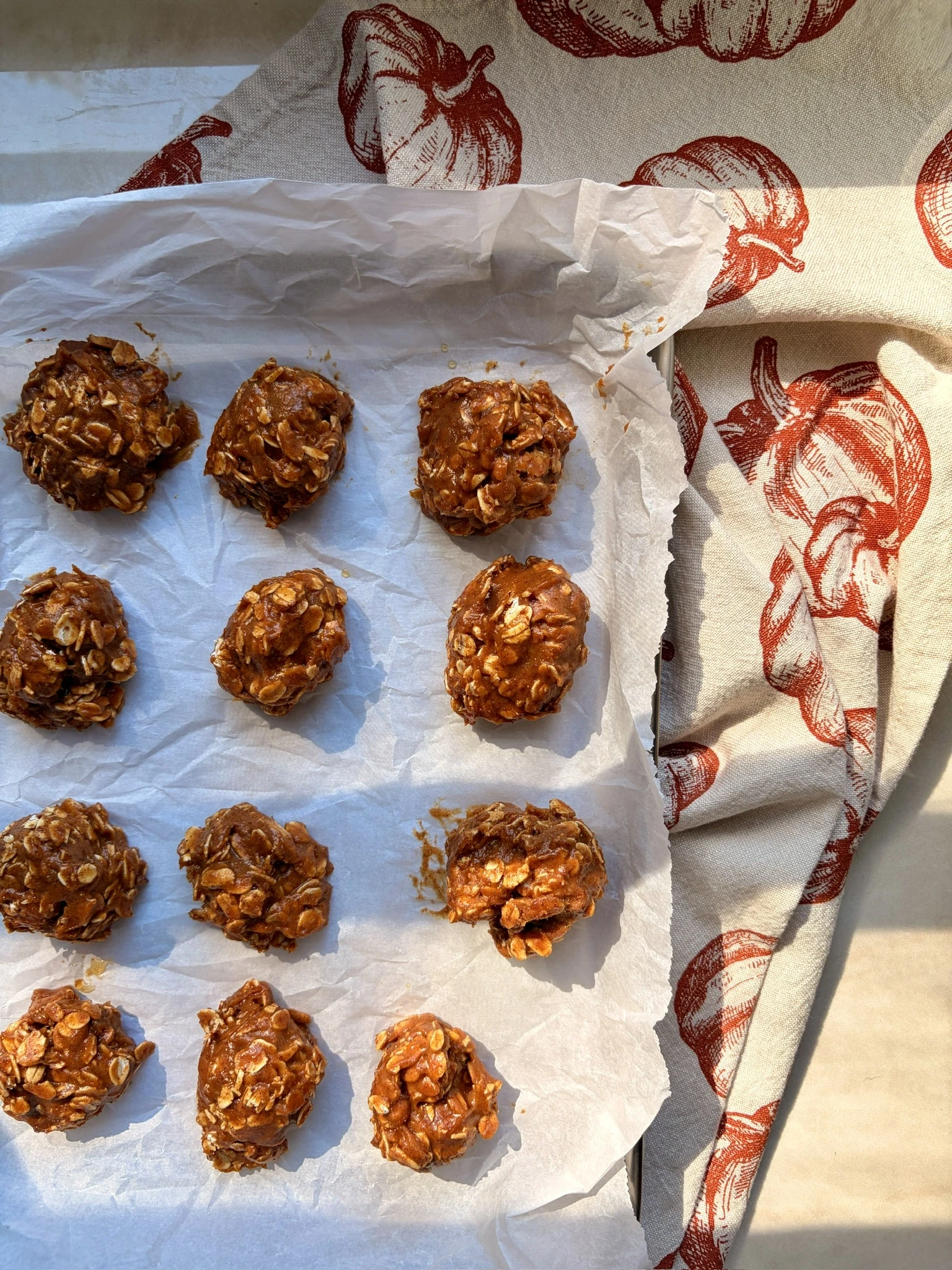 Pumpkin pie protein balls shaped into small rounds and arranged on a baking sheet, made from pumpkin puree, almond butter, maple syrup, gluten-free oats, protein powder, cinnamon, and pumpkin pie spice.