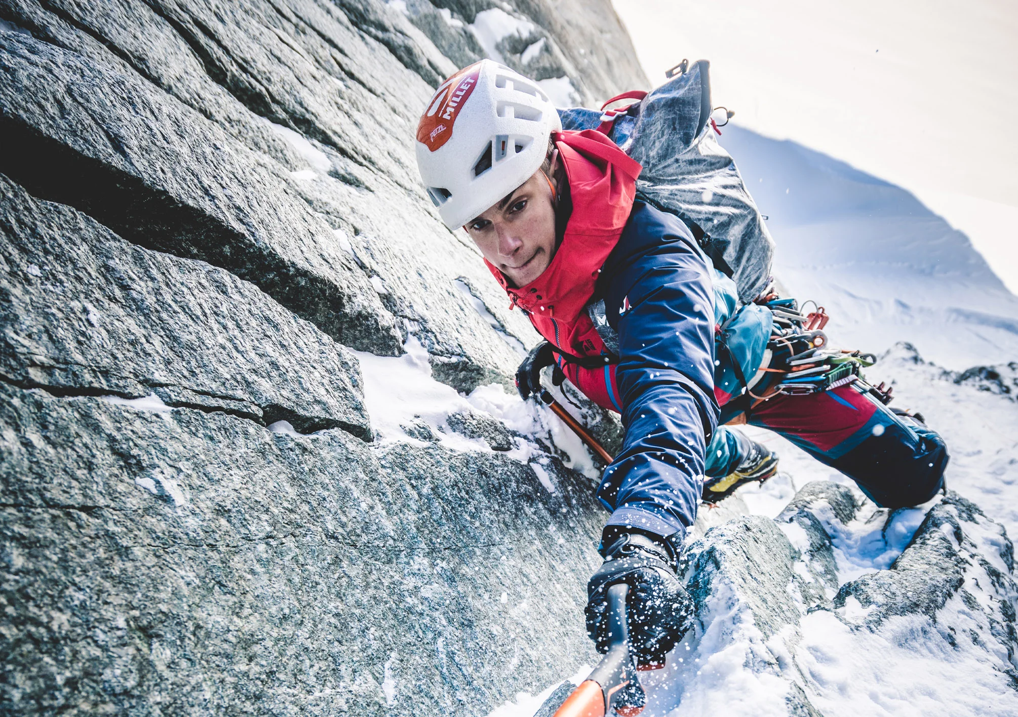 Alpiniste Millet escaladant une paroi rocheuse enneigée dans le massif du Mont-Blanc