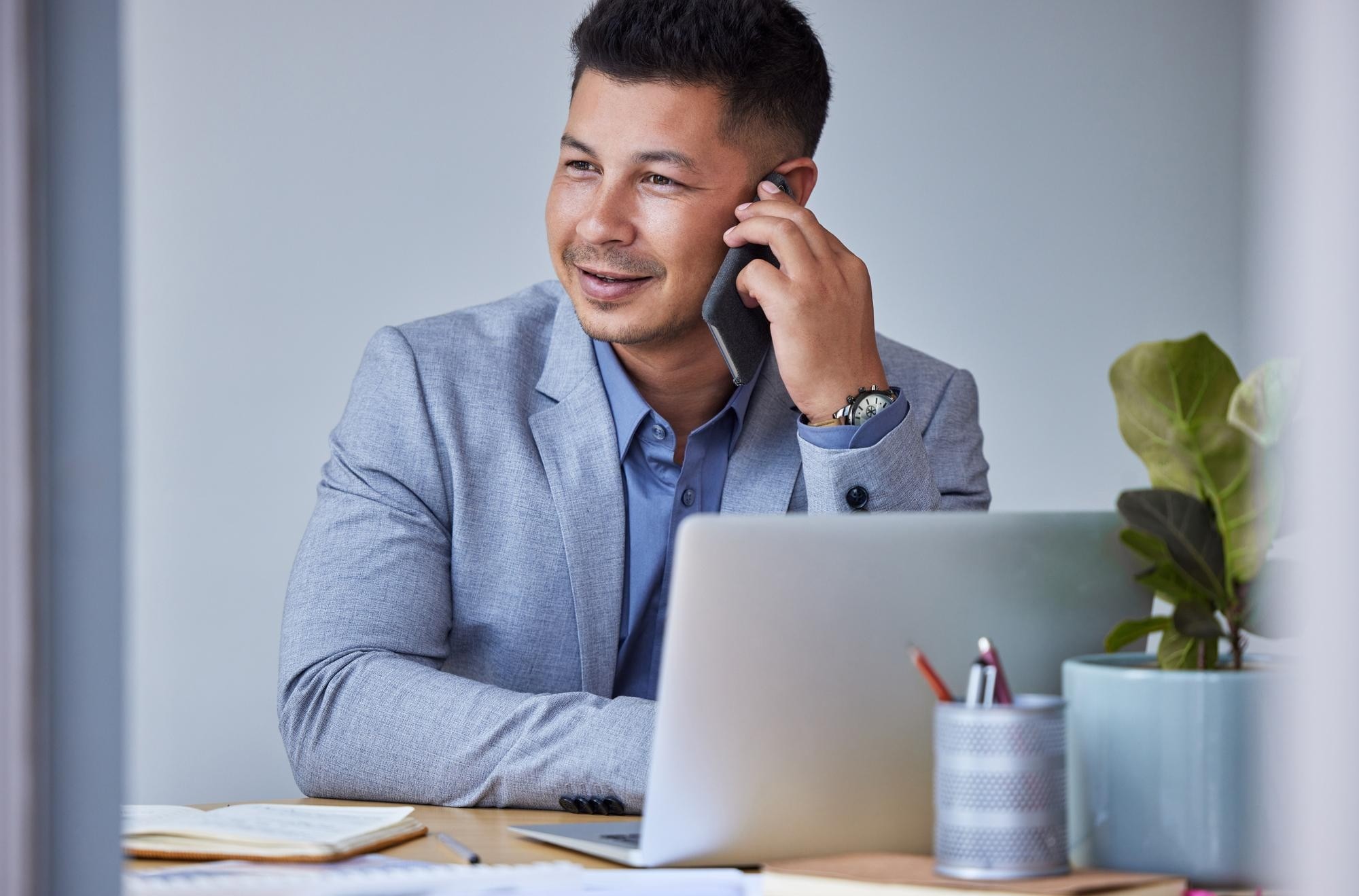 Makelaar belt over een woning terwijl een AI-receptionist op kantoor klantenoproepen aanneemt