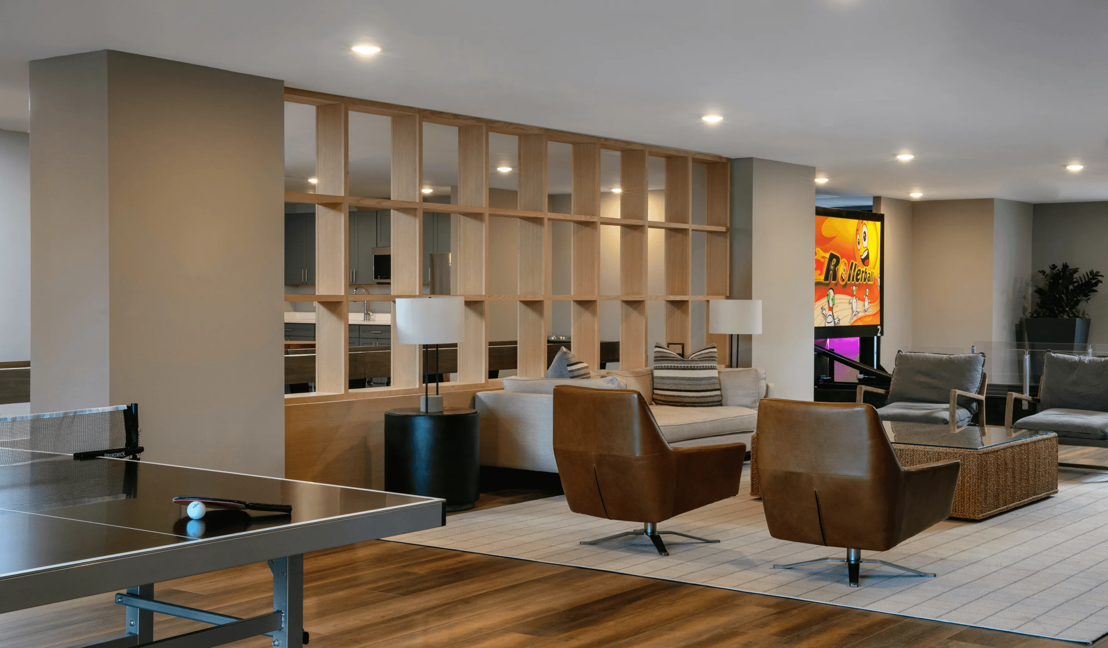 Modern living room with stylish chairs, a large bookshelf, and soft lighting, creating a cozy atmosphere.