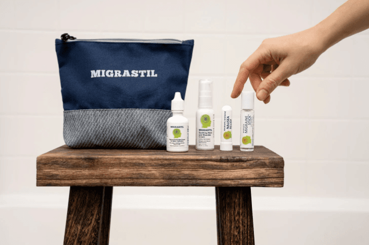 Man wearing a beanie and shirt works on a laptop.