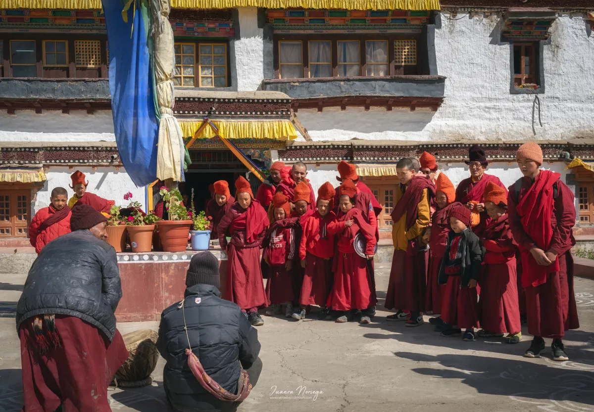 Jóvenes monjes con túnicas granates reunidos en el patio de un monasterio de Zanskar