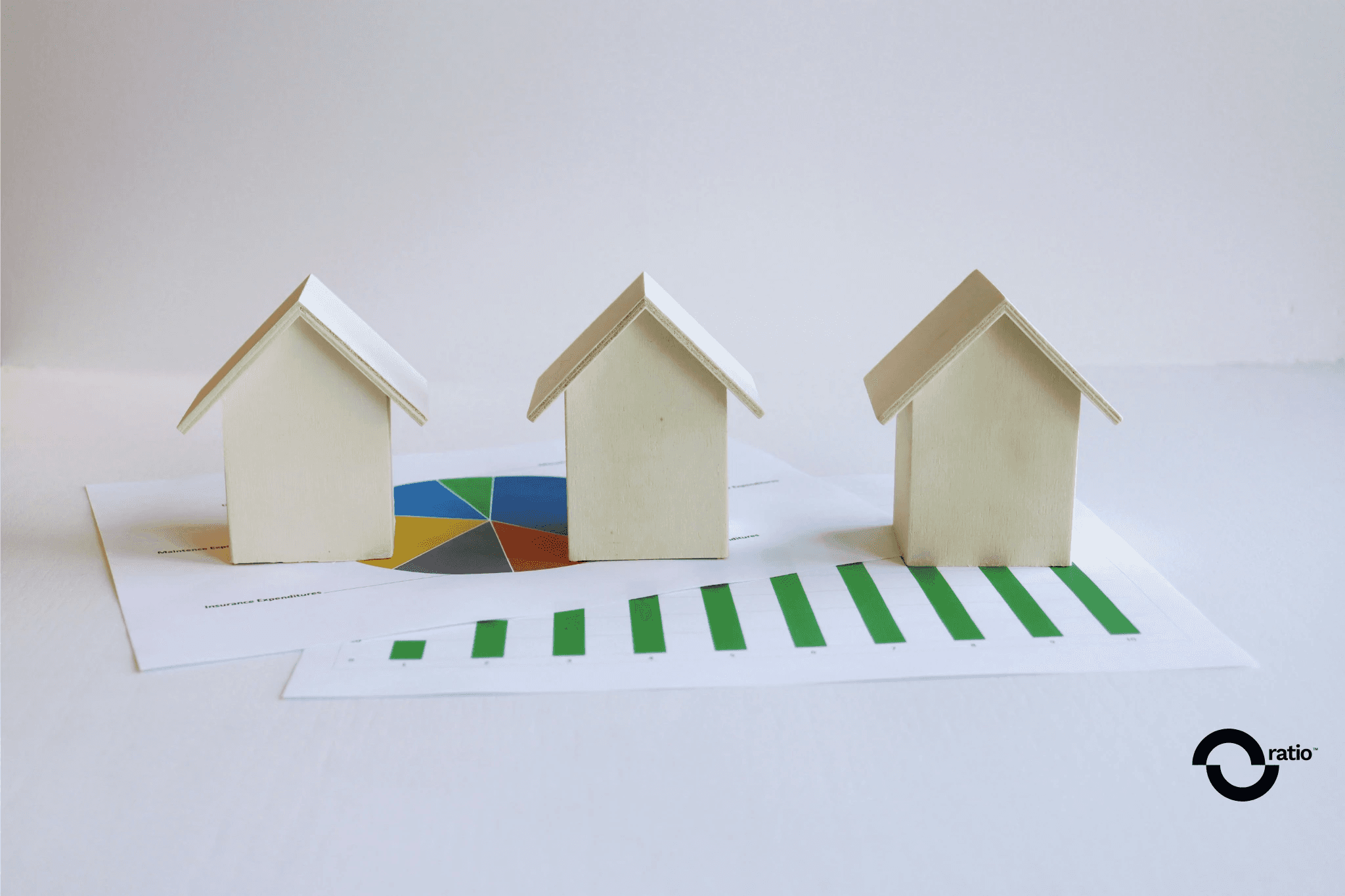 Tres maquetas de casas sobre un gráfico financiero, simbolizando la inversión inmobiliaria.