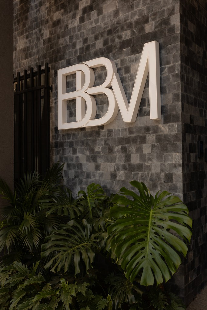 Logo da BBM Advocacia em destaque na fachada do escritório com ambiente corporativo e paisagismo interno.