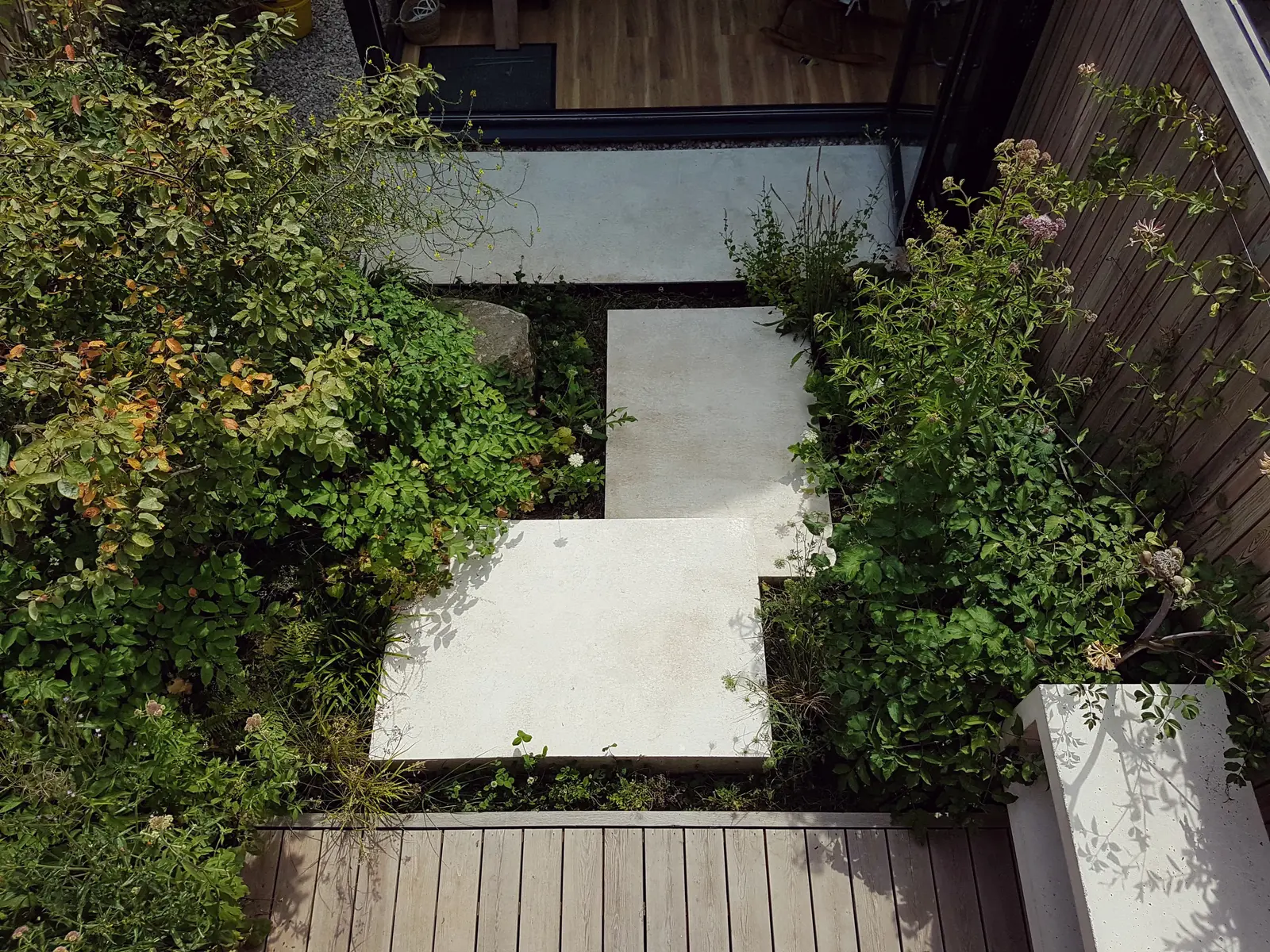 Aerial view of a garden pathway with greenery and stone tiles, creating a serene outdoor space.
