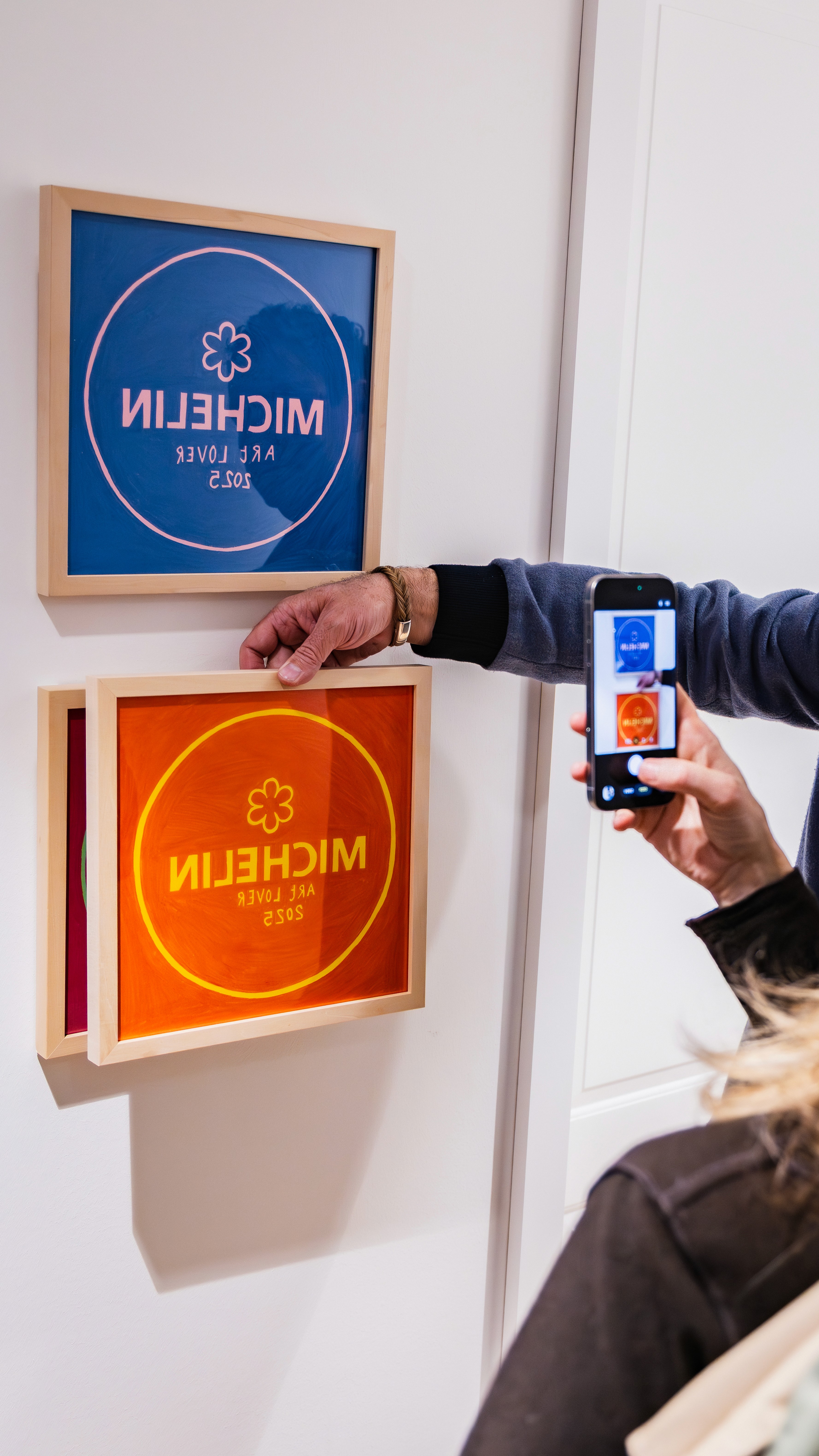 A guest photographing blue and red artworks styled like Michelin plaques.