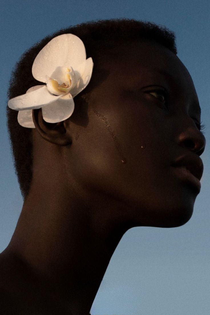 braided woman taking photo beside yellow painted wall