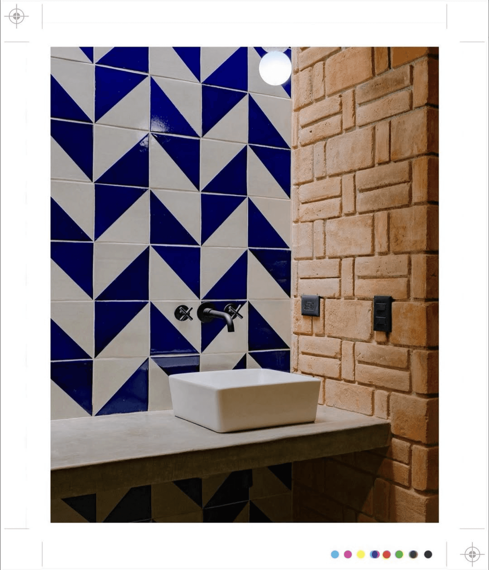 Badkamer met blauw-witte tegels, bakstenen muur en witte wastafel.