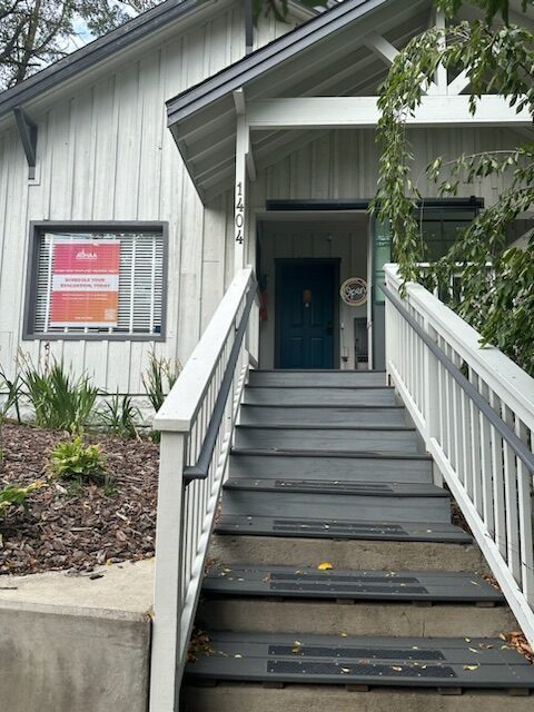 Winding hiking trail through grassy mountainside with trees.
