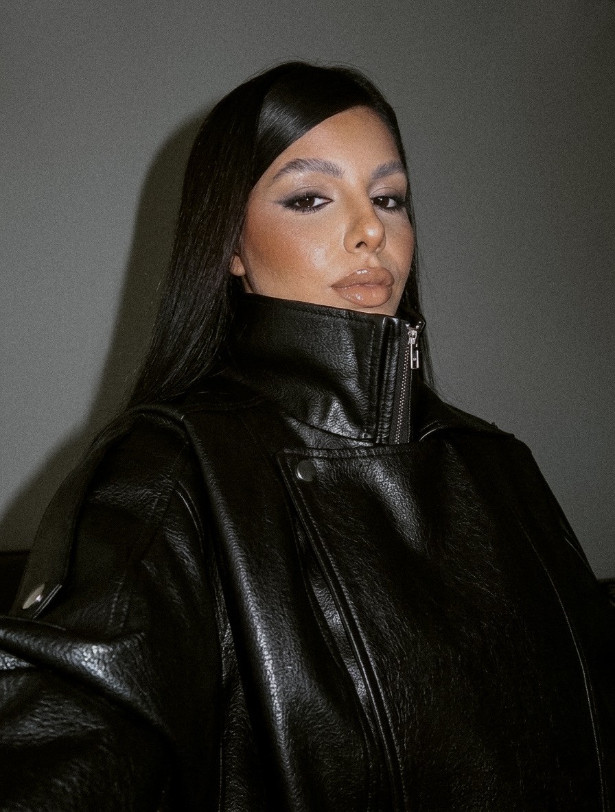 Woman with long dark hair wearing a black leather jacket