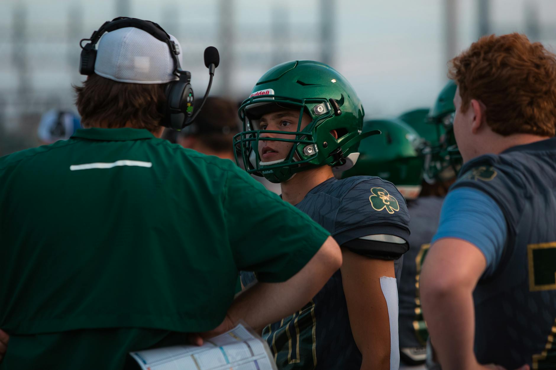 High school quarterback receiving instruction from a college coach during a camp session