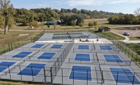 Aerial view of a multi-court pickleball facility with blue and gray surfacing