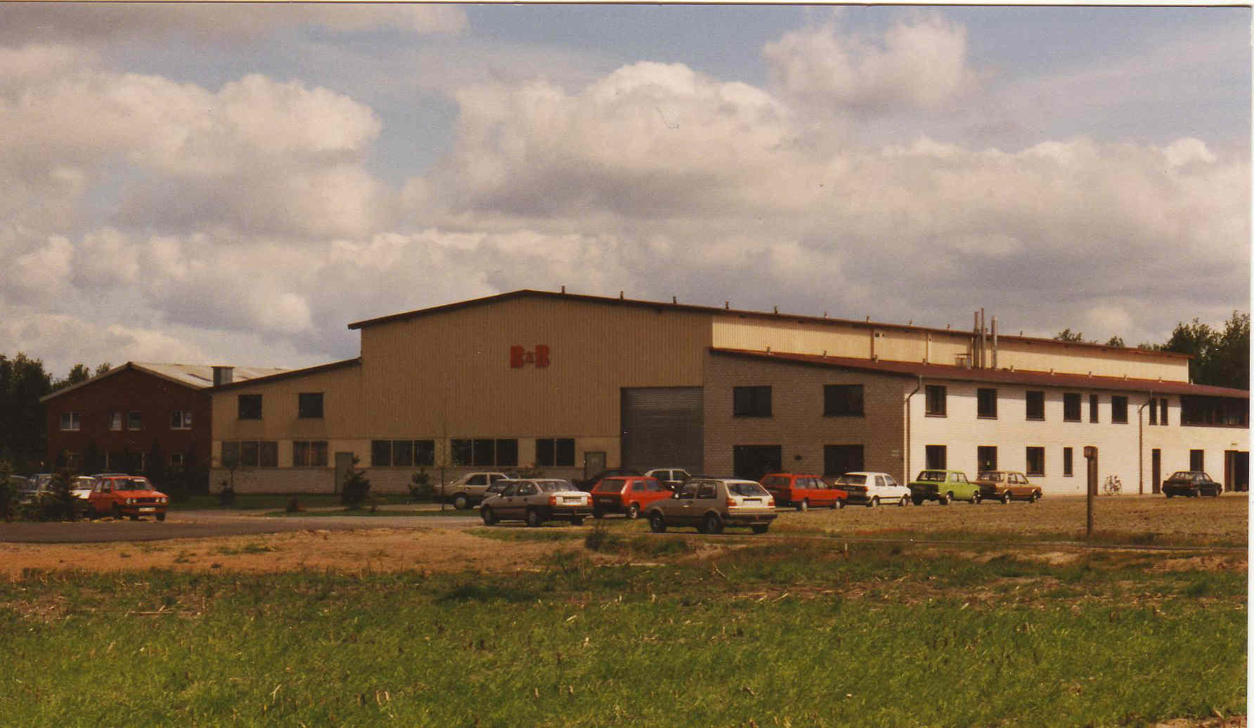 Industriegebäude mit Parkplatz und Autos. Firmengebäude