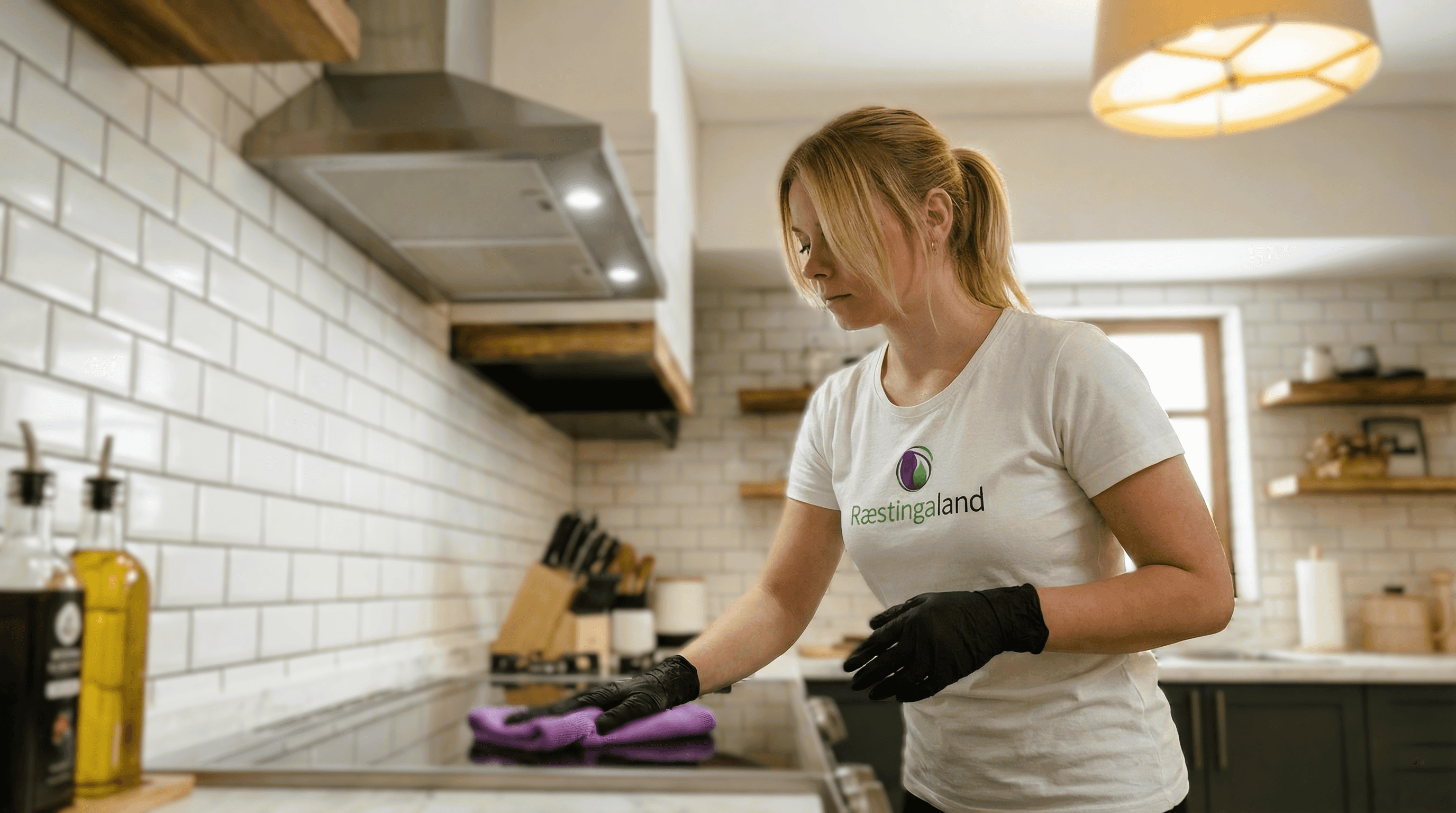 Starfsmaður að þurrka rykk af efri skápum og hillum í eldhúsi á heimili.