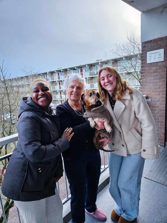 Twee VoorUiters met een buurtbewoner en haar hond op de galerij