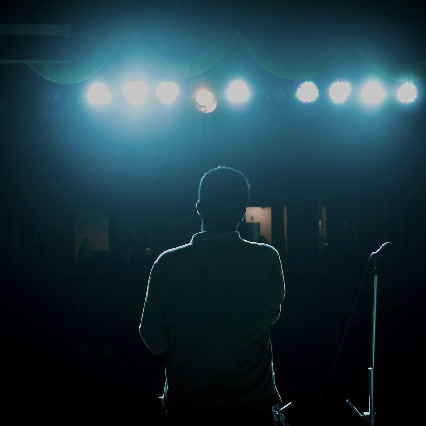 A speaker at a microphone stand under stage lights