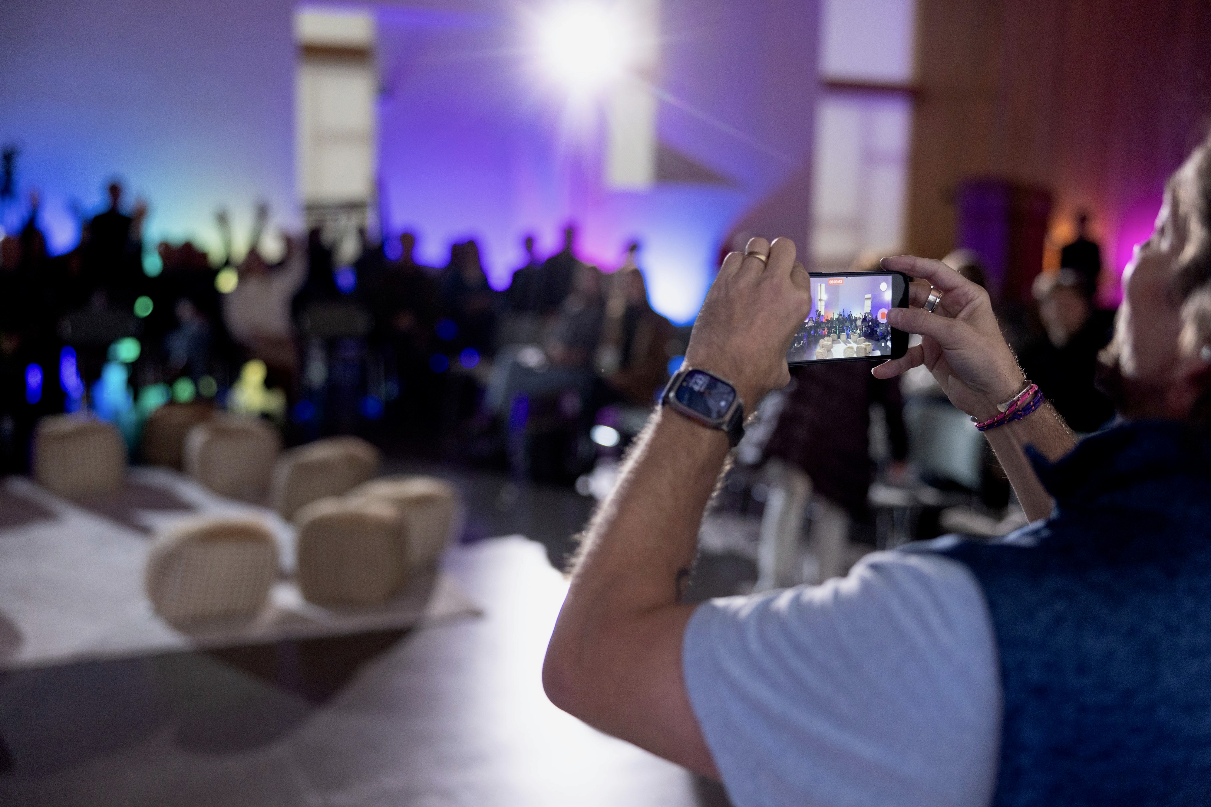 A restaurant interior featuring marble countertops, brown leather chairs, wood-paneled walls, and round pendant lights hanging above a bar set with wine glasses.