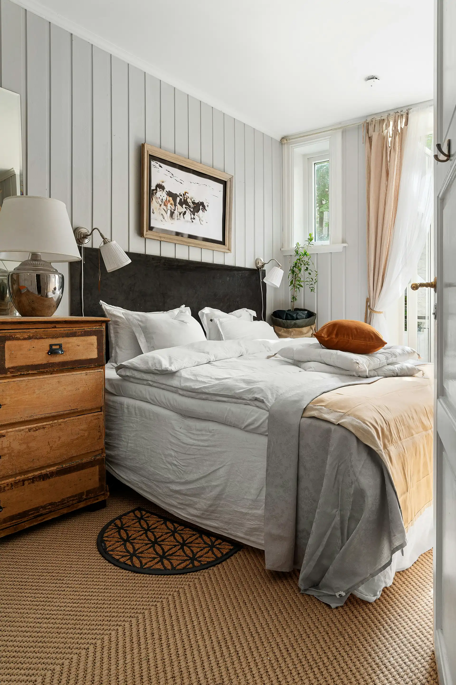 Spacious bedroom with large windows, wooden flooring, and natural light
