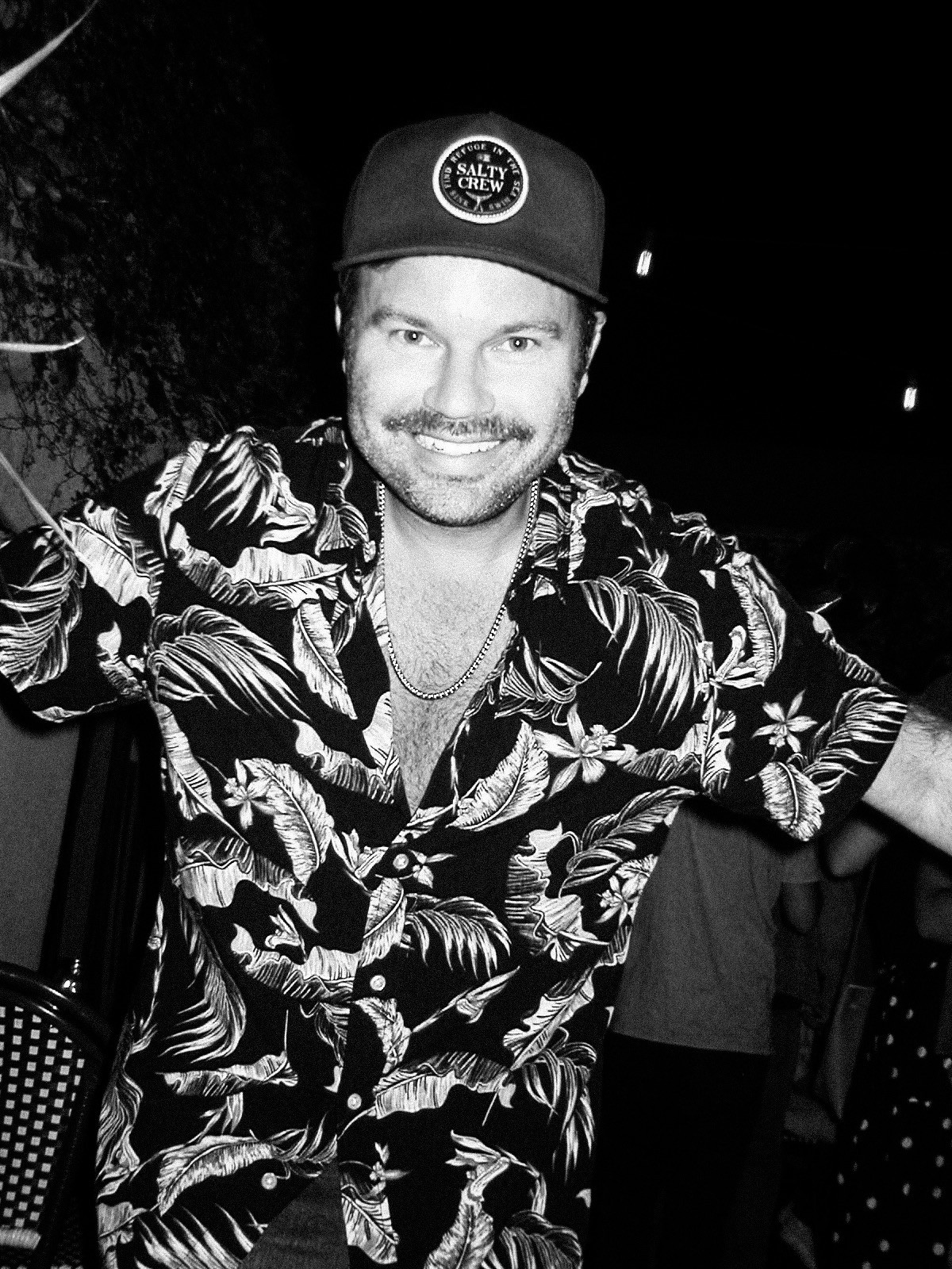 A thoughtful young person with dark hair gazes to the side, captured in soft black and white lighting.