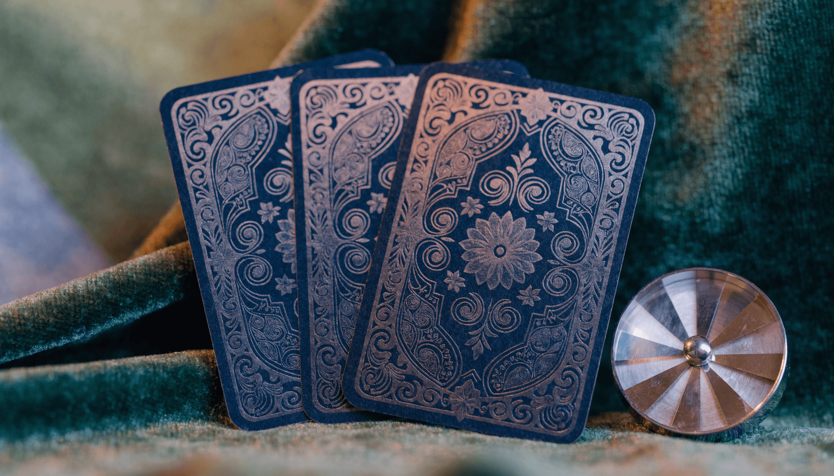 A realistic macro photograph of three Tarot cards laid out on a bed of dark #2E4032 Mossy Green velvet. The lighting is "calid" and warm, using #8C7D64 Aged Bronze highlights to pick up the texture of the card edges