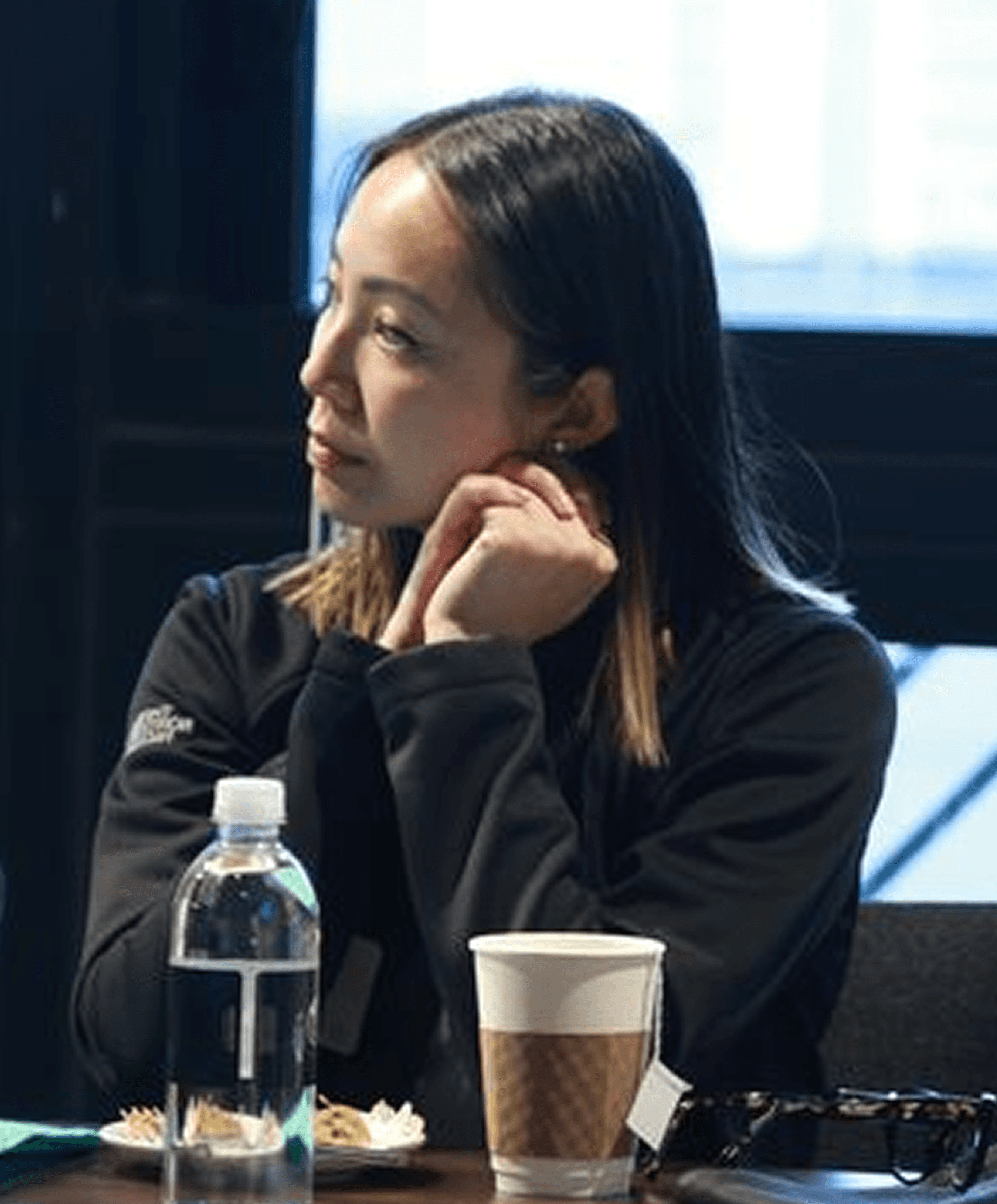 Modern office space with large arched windows, white furniture, and blurred figures walking through.