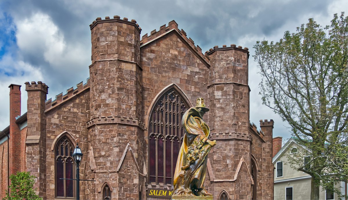 The Salem Witch Museum building and the Roger Conant statue under an autumn sky