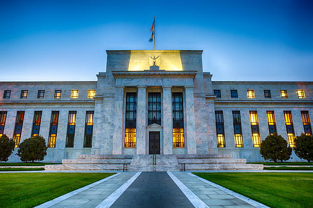 Federal Reserve headquarters building in Washington D.C. illuminated at dusk, with marble columns and American flag