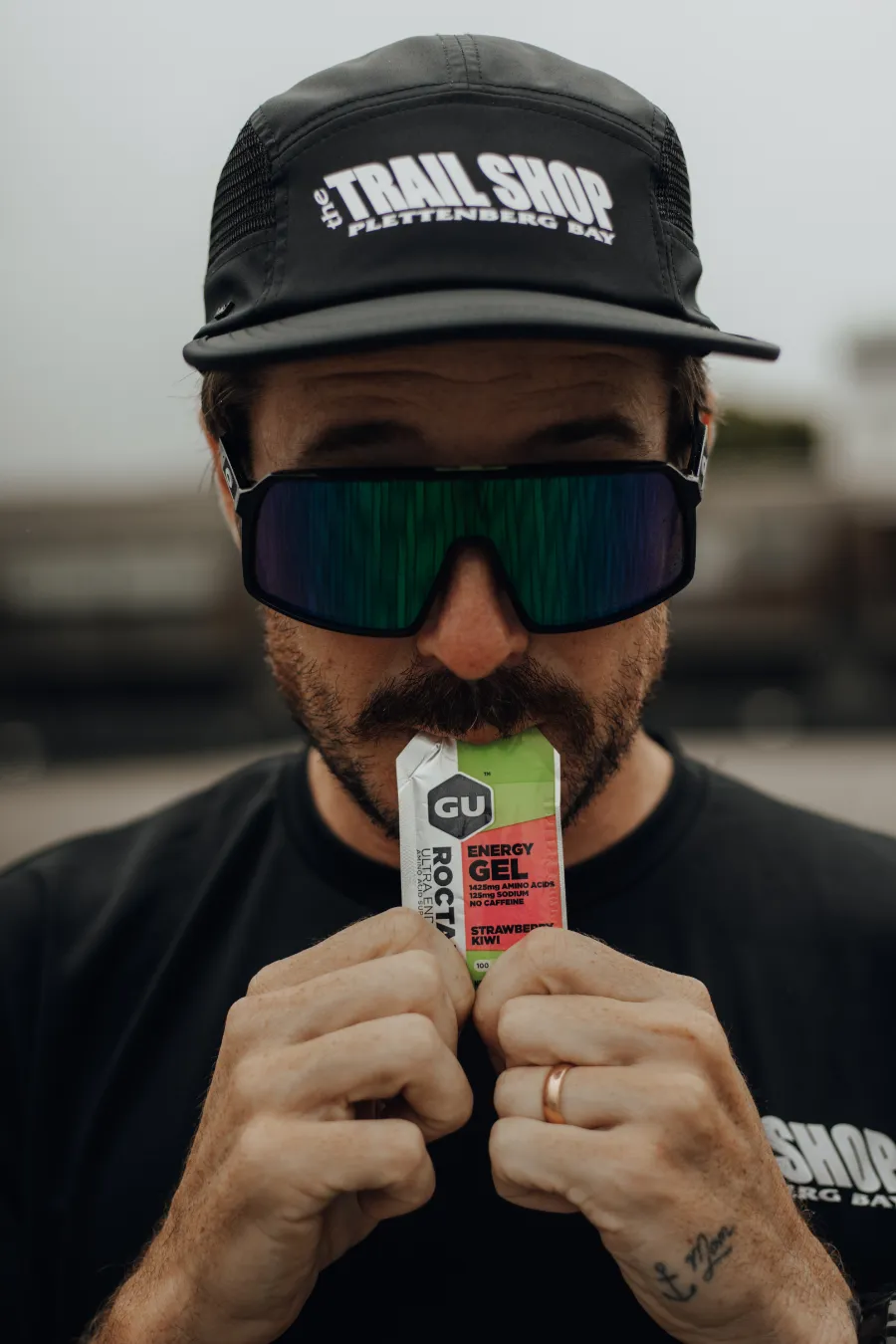 Johnny Wolf wearing The Trail Shop cap while holding a GU Gel
