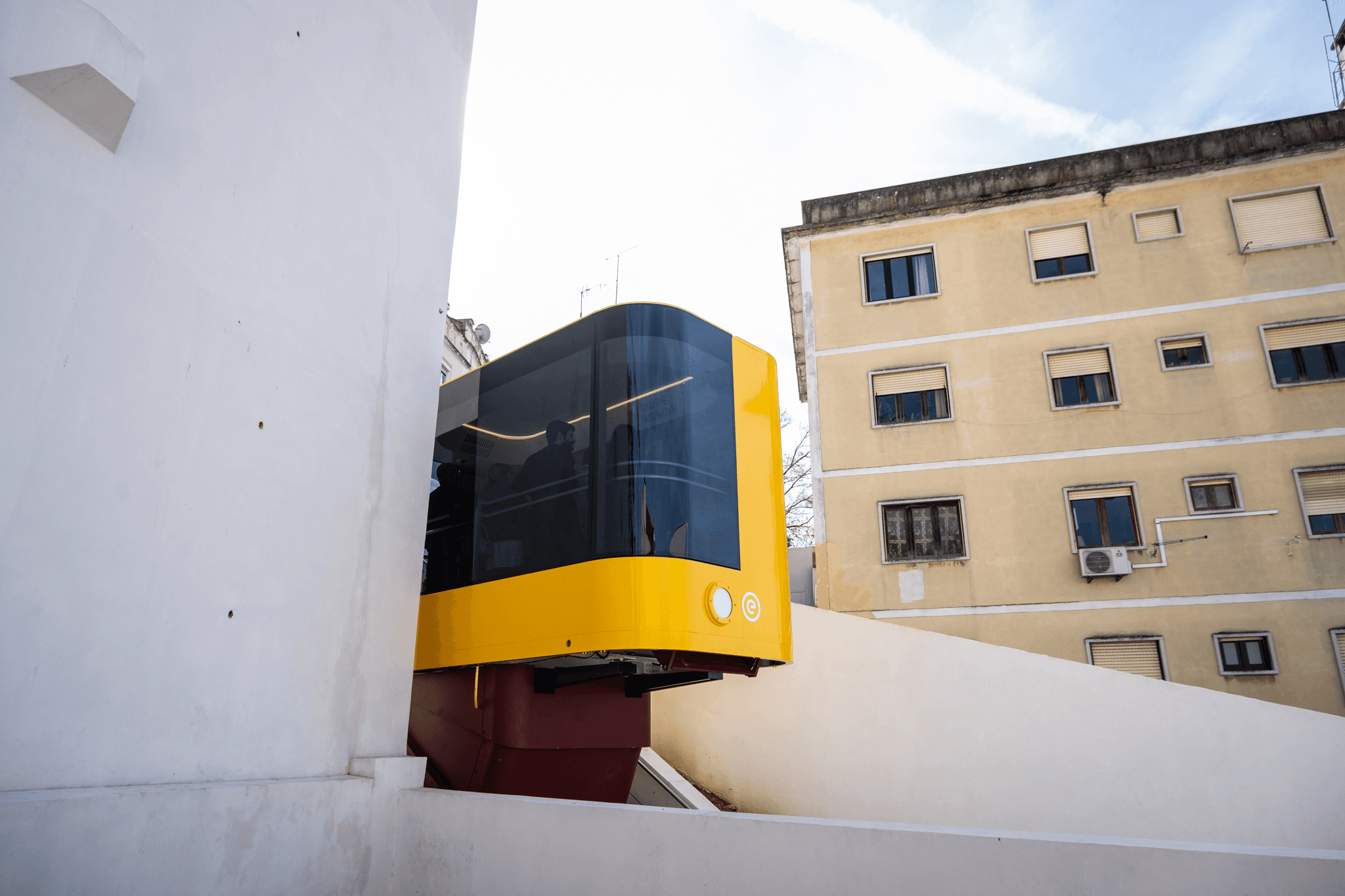 Modern yellow Funicular da Graça between buildings in Lisbon