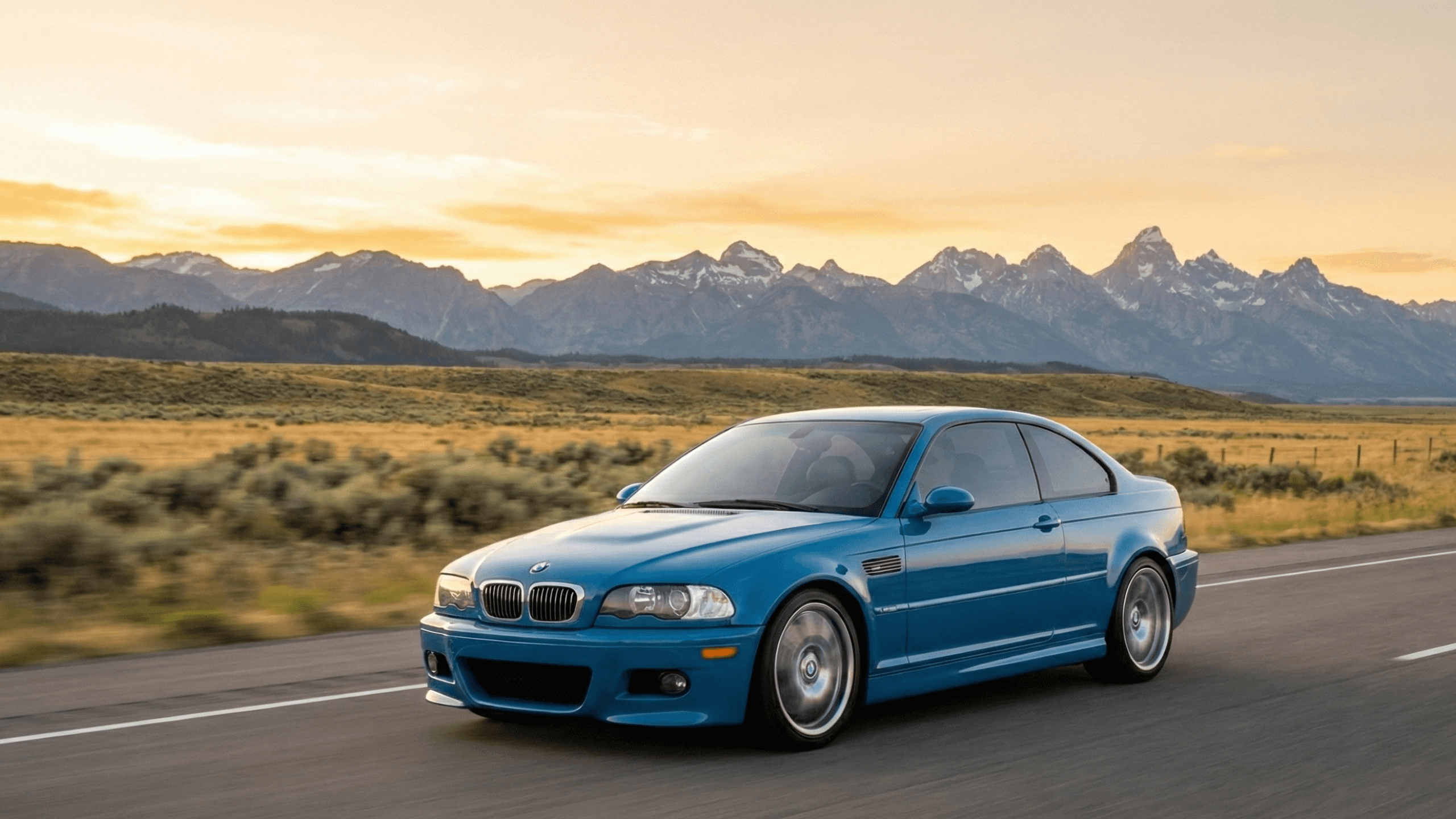 BMW E46 M3 driving on a Wyoming road at sunset