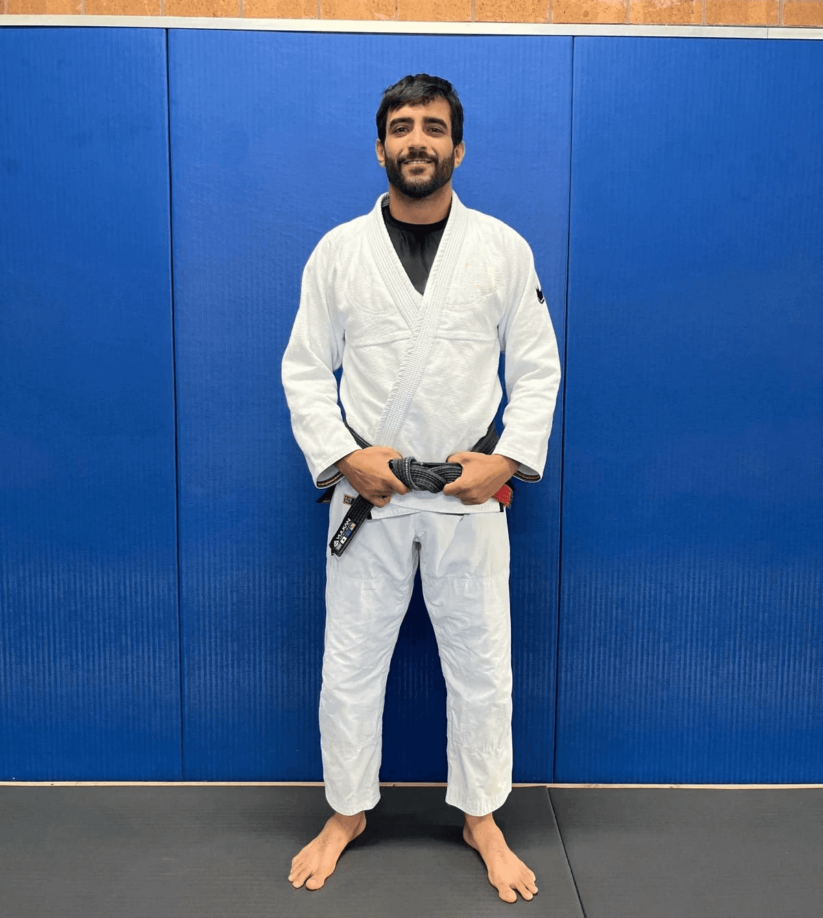 Maria Elisa Thimoteo smiling in her gi, hands folded in front of a gradient backdrop