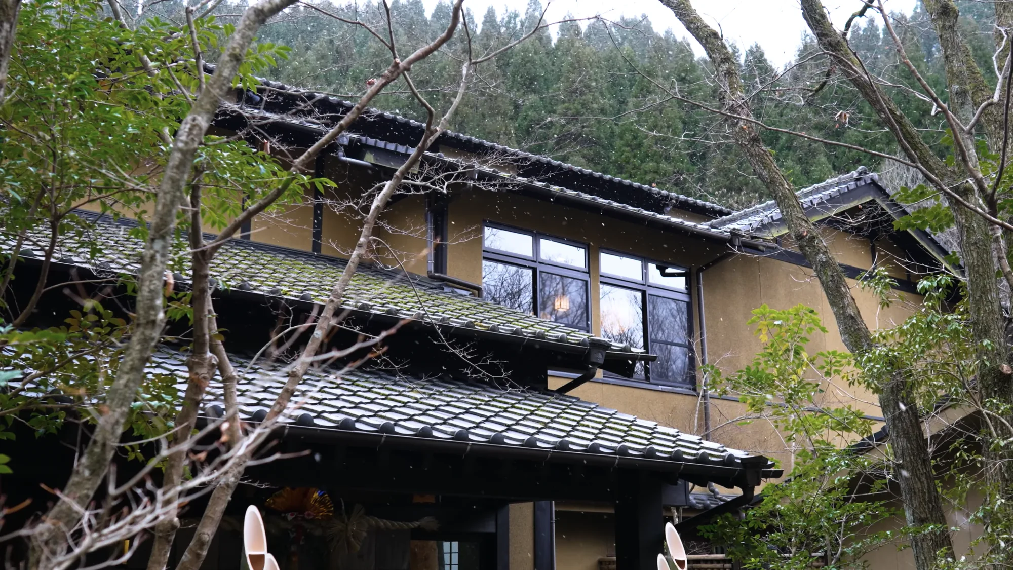 An ochre inn facade at Kurokawa Onsen with wide eaves and parasols set out front