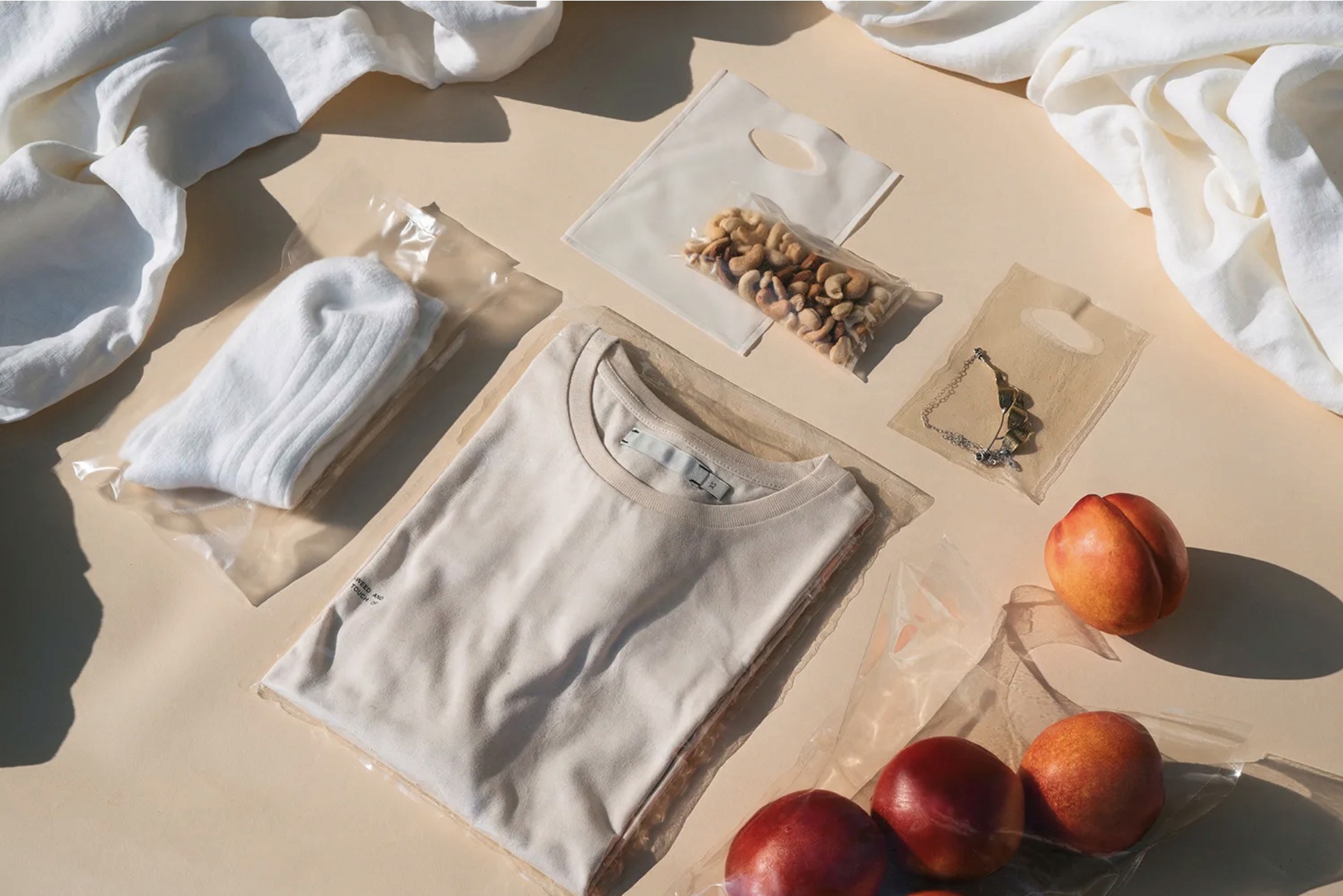 A photo of some cream packed t-shirt, white socks, seed bags and some red fruits.