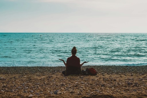 person doing yoga on seashore during daytime