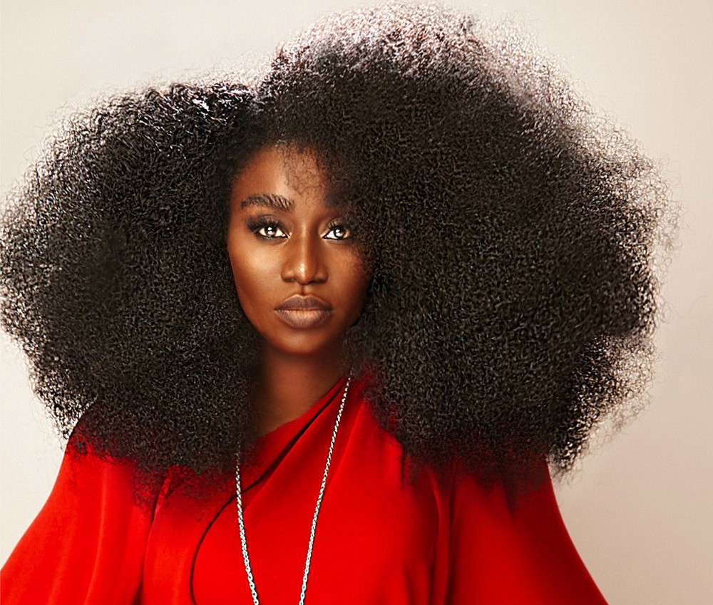 A young man with dark hair smiles at the camera, set against a modern indoor background.