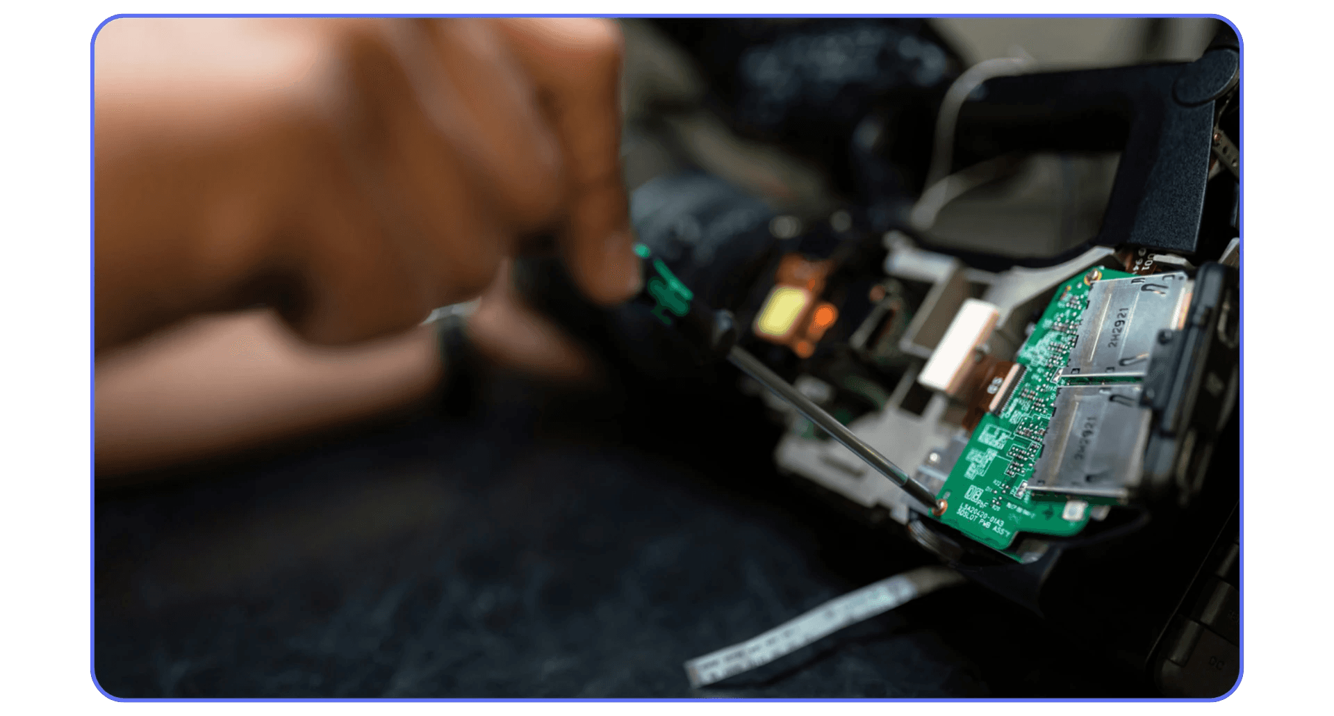 Technician repairing internal computer hardware components, focusing on circuit board and connection ports.