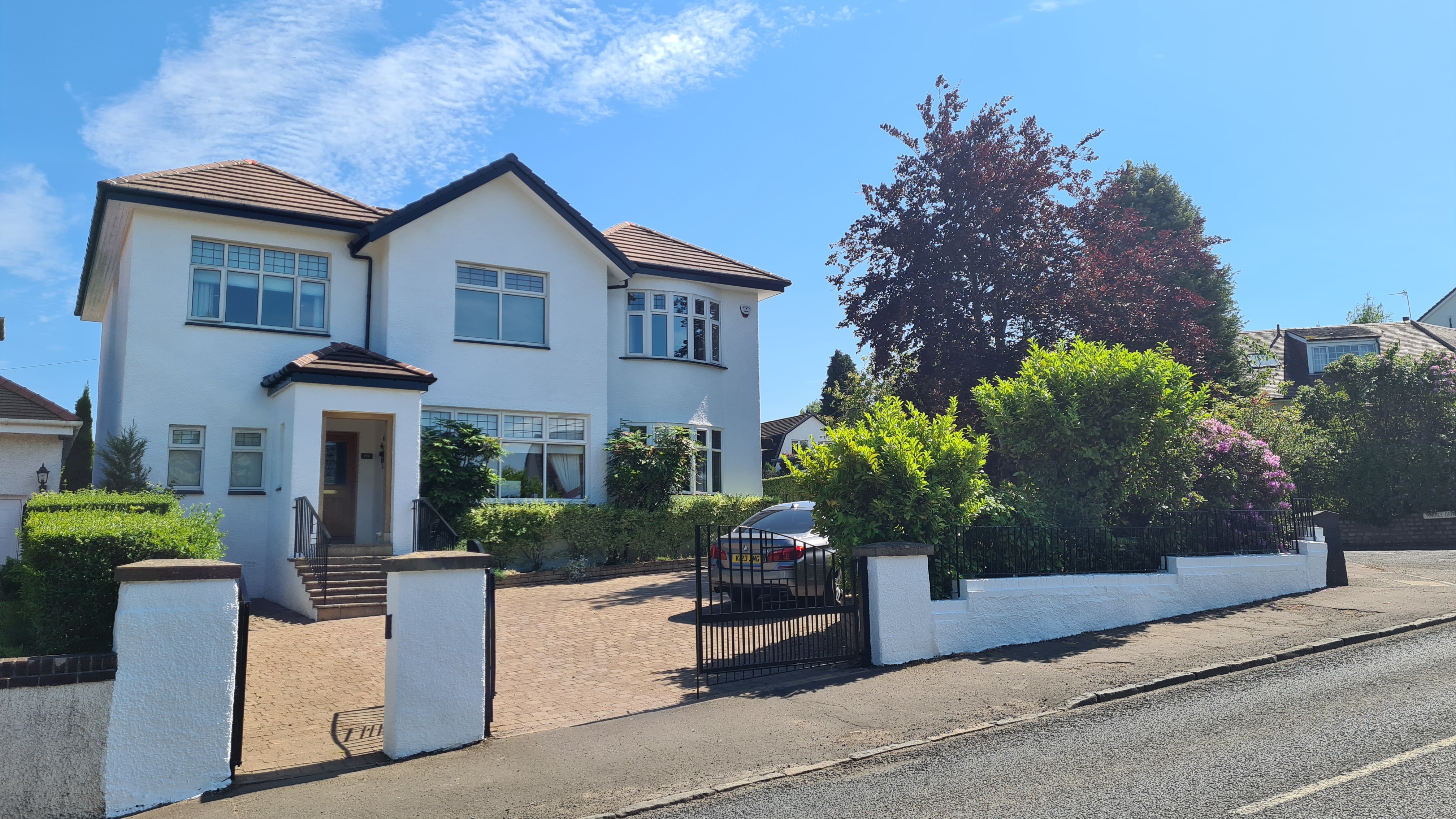 A house white large gated driveway with a car on it