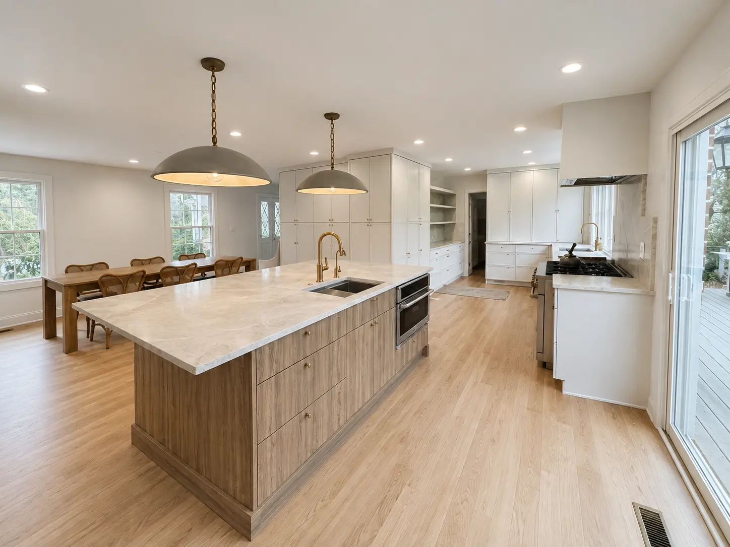 Bright open-concept kitchen remodel featuring a large wood island, light stone countertops, white cabinetry, pendant lighting, and hardwood floors.